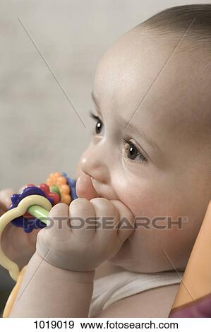 Stock Photo - A baby gnawing on a teething ring. Fotosearch