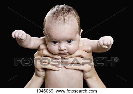 Stock Photo - A baby held aloft staring down. Fotosearch