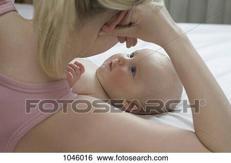 A baby lying down looking up at her mother lying beside her View Large Photo Image Stock Photograph - A baby lying down looking up at her mother lying beside her. Fotosearch