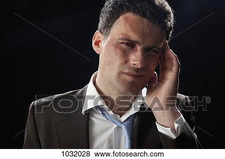 A beaten up businessman wincing in pain View Large Photo Image Stock Photo - A beaten up businessman wincing in pain. Fotosearch