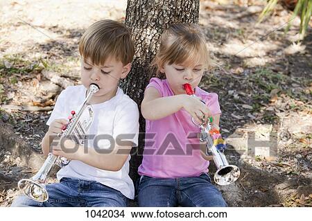 Picture - A boy and a girl sitting and playing toy musical instruments. Fotosearch