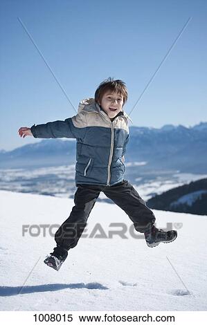 A boy jumping on a snowy mountain View Large Photo Image Stock Photography - A boy jumping on a snowy mountain. Fotosearch