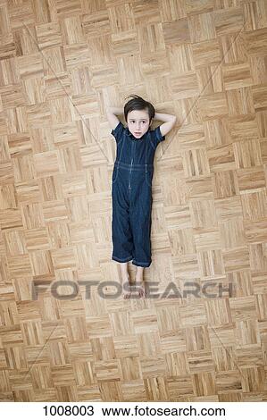 Stock Image - A boy lying on the floor with hands behind his head. Fotosearch