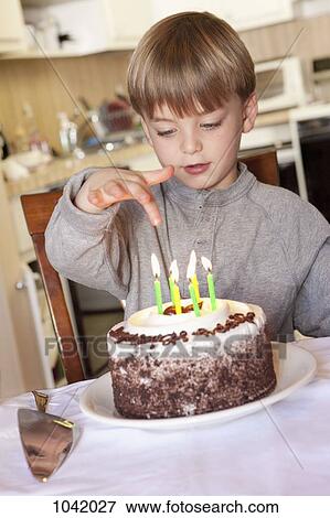 A boy sitting behind a birthday cake with lit candles View Large Photo Image Stock Photo - A boy sitting behind a birthday cake with lit candles. Fotosearch