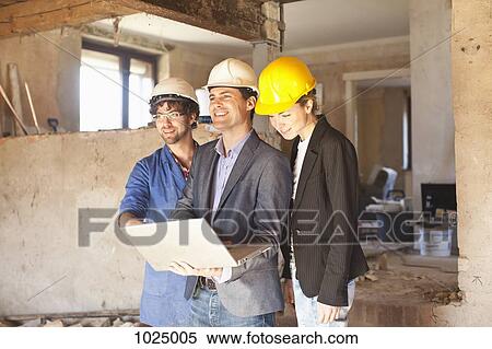 A building contractor and architects looking at a laptop at a building site View Large Photo Image Stock Photography - A building contractor and architects looking at a laptop at a building site. Fotosearch