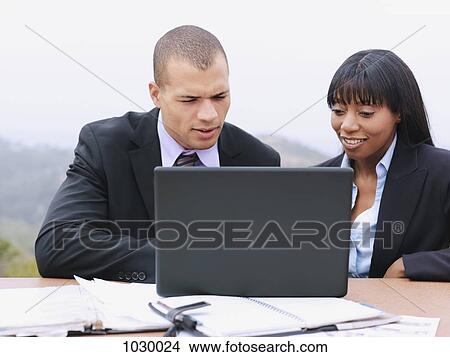 A businessman and a businesswoman using a laptop together View Large Photo Image Picture - A businessman and a businesswoman using a laptop together. Fotosearch
