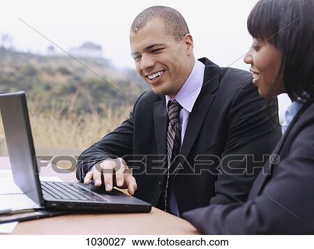 A businessman and a businesswoman using a laptop together View Large Photo Image Stock Photo - A businessman and a businesswoman using a laptop together. Fotosearch