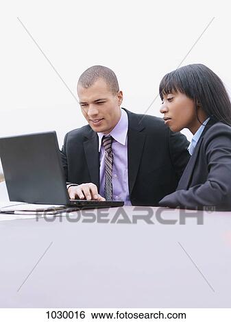 A businessman and a businesswoman using a laptop together View Large Photo Image Stock Photograph - A businessman and a businesswoman using a laptop together. Fotosearch