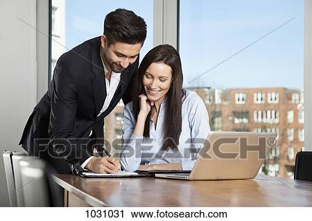 Stock Image - A businessman and businesswoman having a meeting in a board room. Fotosearch