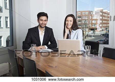 Stock Photograph - A businessman and businesswoman having a meeting in a board room. Fotosearch