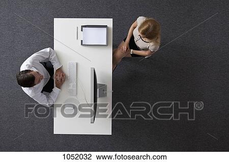 A businessman and businesswoman sitting across a desk from each other, overhead view View Large Photo Image Stock Image - A businessman and businesswoman sitting across a desk from each other, overhead view. Fotosearch