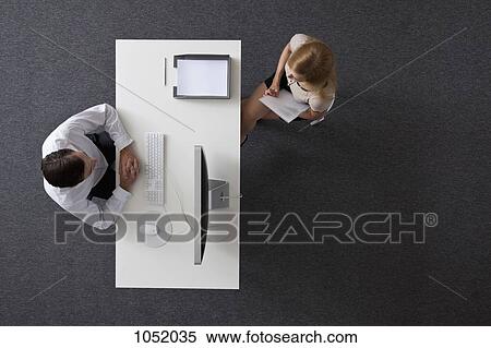 A businessman and businesswoman sitting across a desk from each other, overhead view View Large Photo Image Stock Photography - A businessman and businesswoman sitting across a desk from each other, overhead view. Fotosearch