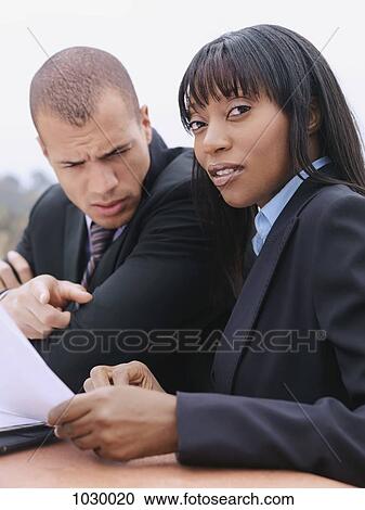 Stock Image - A businessman and businesswoman reviewing a document. Fotosearch
