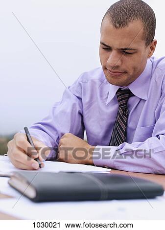 Stock Image - A businessman doing paperwork. Fotosearch