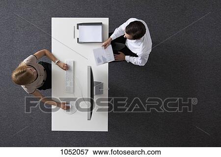 A businessman giving papers to a businesswoman sitting at a desk, overhead view View Large Photo Image Stock Photo - A businessman giving papers to a businesswoman sitting at a desk, overhead view. Fotosearch
