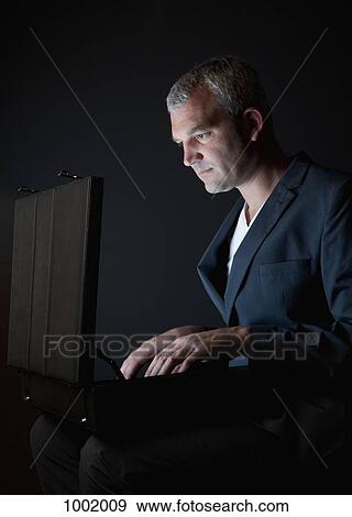 A businessman looking in a briefcase emitting light View Large Photo Image Stock Photo - A businessman looking in a briefcase emitting light. Fotosearch