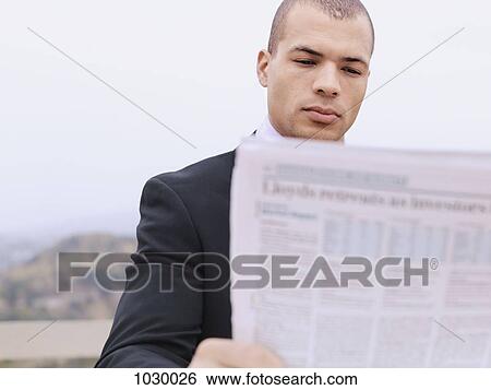 A businessman on a break reading a newspaper outdoors View Large Photo Image Stock Photograph - A businessman on a break reading a newspaper outdoors. Fotosearch