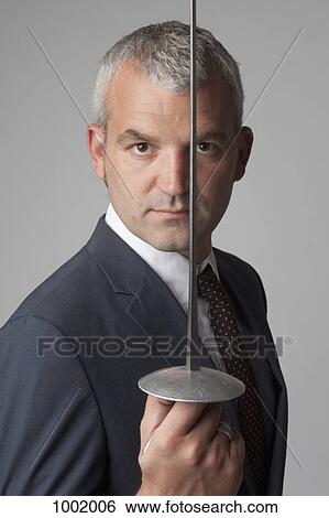 A businessman posing with a fencing sword View Large Photo Image Stock Photograph - A businessman posing with a fencing sword. Fotosearch
