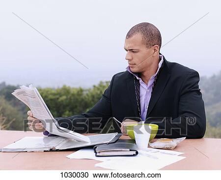 A businessman reading a newspaper and having breakfast outdoors View Large Photo Image Stock Image - A businessman reading a newspaper and having breakfast outdoors. Fotosearch