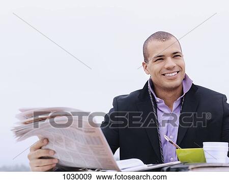 A businessman reading a newspaper and having breakfast outdoors View Large Photo Image Stock Photo - A businessman reading a newspaper and having breakfast outdoors. Fotosearch