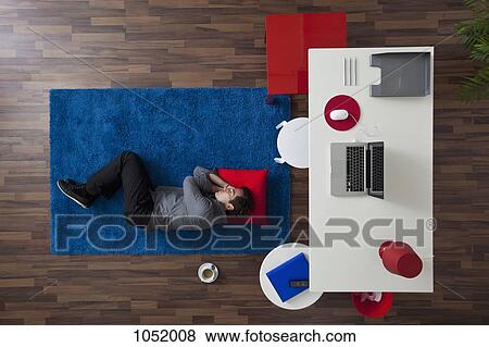 A businessman sleeping on a rug near his desk, overhead view View Large Photo Image Stock Photo - A businessman sleeping on a rug near his desk, overhead view. Fotosearch