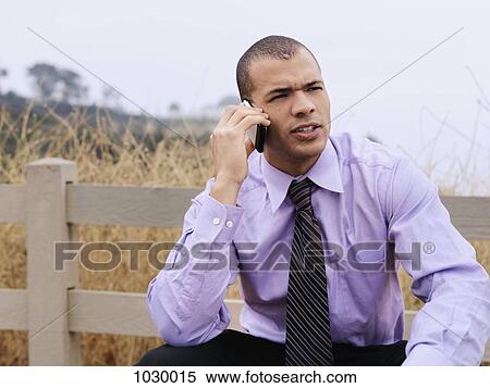 A businessman talking on a mobile phone outdoors View Large Photo Image Stock Photography - A businessman talking on a mobile phone outdoors. Fotosearch