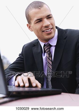 Stock Photo - A businessman using a laptop, outdoors. Fotosearch