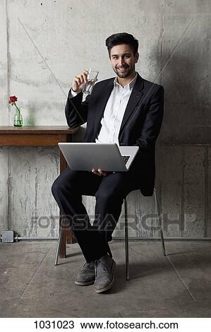 A businessman with a laptop holding a glass of water View Large Photo Image Stock Image - A businessman with a laptop holding a glass of water. Fotosearch