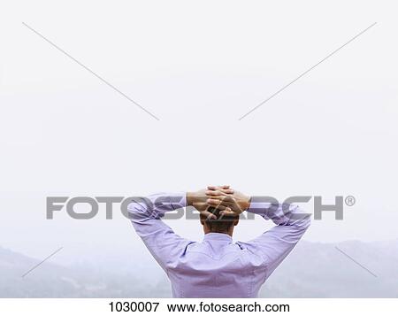 A businessman with his hands behind his head looking at the view, outdoors View Large Photo Image Stock Photo - A businessman with his hands behind his head looking at the view, outdoors. Fotosearch