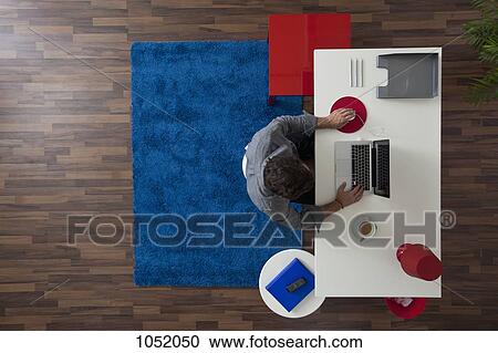 A businessman working at his desk in his home office, overhead view View Large Photo Image Stock Image - A businessman working at his desk in his home office, overhead view. Fotosearch