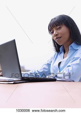 Stock Photograph - A businesswoman using a laptop, outdoors. Fotosearch