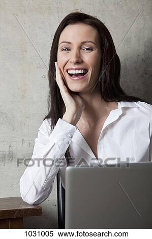 A businesswoman with a laptop laughing View Large Photo Image Stock Photography - A businesswoman with a laptop laughing. Fotosearch