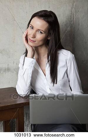 Stock Image - A businesswoman with a laptop smiling at the camera. Fotosearch