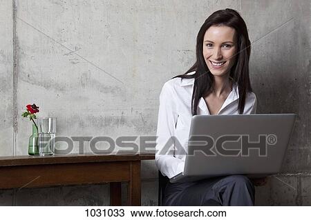 A businesswoman with a laptop smiling at the camera View Large Photo Image Stock Image - A businesswoman with a laptop smiling at the camera. Fotosearch
