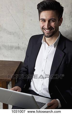 A cheerful businessman with a laptop, high angle view View Large Photo Image Stock Photo - A cheerful businessman with a laptop, high angle view. Fotosearch