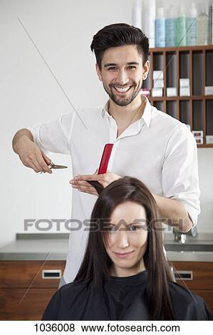 Stock Photo - A cheerful male hairdresser cutting a woman's hair . Fotosearch