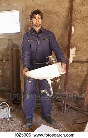 A construction worker carrying a sink at a building site View Large Photo Image Stock Photograph - A construction worker carrying a sink at a building site. Fotosearch