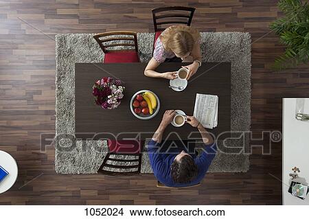 A couple having morning coffee together at a dining room table, overhead view View Large Photo Image Picture - A couple having morning coffee together at a dining room table, overhead view. Fotosearch