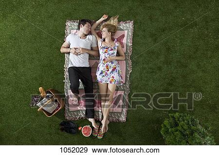A couple lying on a blanket in a park looking at each other romantically, overhead view View Large Photo Image Stock Photo - A couple lying on a blanket in a park looking at each other romantically, overhead view. Fotosearch