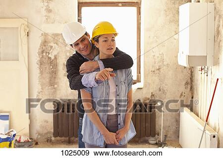 Stock Photo - A couple standing in their house that's under renovation. Fotosearch