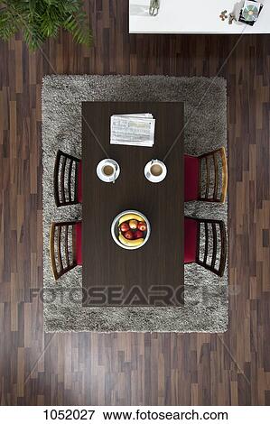 Stock Photo - A dining table with coffee cups and newspaper, overhead view. Fotosearch