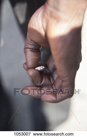 Stock Photo - A dirty hand holding a cigarette. Fotosearch