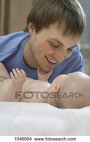 A father smiling while bonding with his baby daughter View Large Photo Image Picture - A father smiling while bonding with his baby daughter. Fotosearch