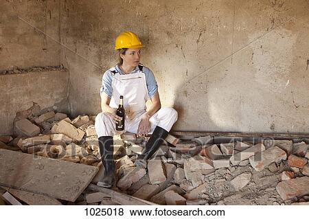A female construction worker sitting on rubble holding a beer View Large Photo Image Stock Photo - A female construction worker sitting on rubble holding a beer. Fotosearch
