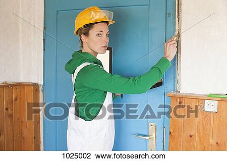Stock Image - A female manual worker applying plaster to a wall. Fotosearch