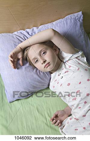 A girl lying on a bed, looking at camera View Large Photo Image Stock Image - A girl lying on a bed, looking at camera. Fotosearch