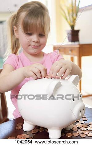 A girl putting coins into a piggy bank View Large Photo Image Picture - A girl putting coins into a piggy bank. Fotosearch