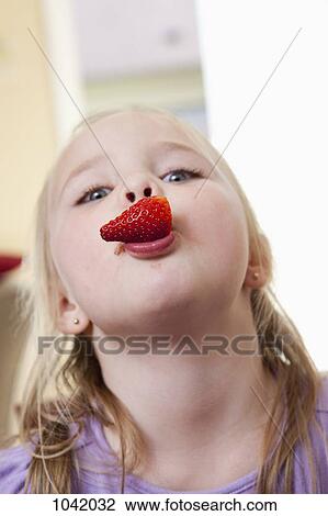 Stock Image - A girl with a strawberry in her mouth. Fotosearch