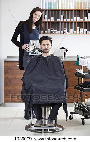 A hairdresser holding a mirror up for customer View Large Photo Image Stock Photo - A hairdresser holding a mirror up for customer. Fotosearch