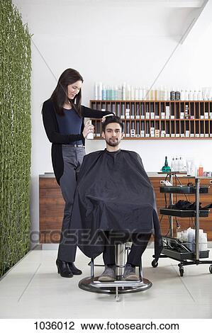 Stock Image - A hairdresser spraying product into a customer's hair. Fotosearch